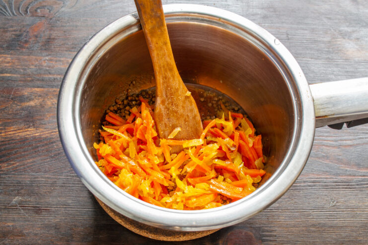Combining Sautéed Vegetables with the Buckwheat Adding the previously sautéed carrots and onions to the pan with buckwheat.