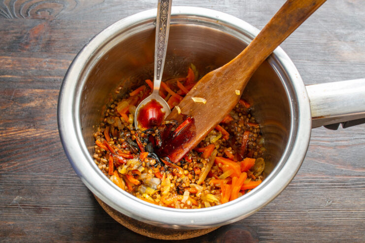 Seasoning the Dish with Spices Spices and soy sauce being added to the buckwheat and vegetable mixture.