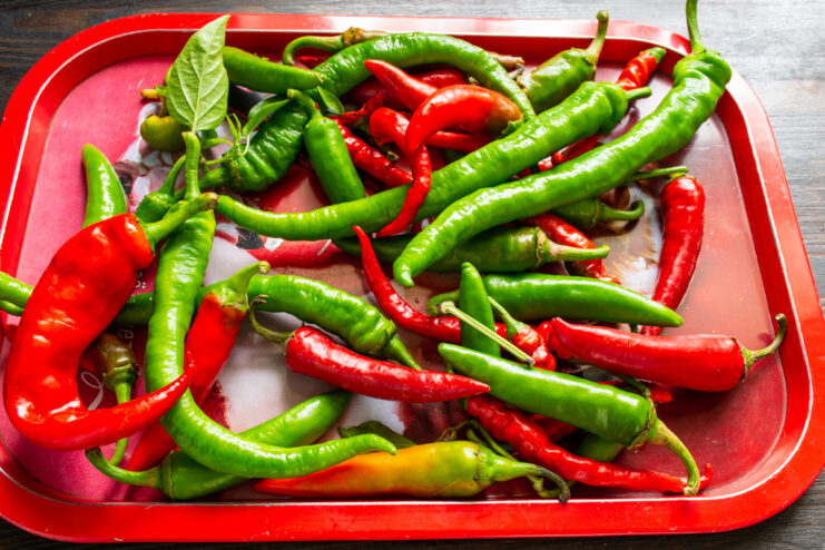Tip: Wither Chili Peppers for a Thicker Adjika Red chili peppers spread out on a white surface to wither before being used in a recipe.