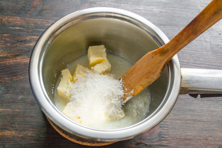 Preparing the Creamy Coconut Glaze Heating cream, butter, sugar, and coconut in a saucepan to make the glaze.