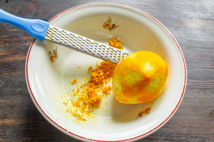 Preparing Oranges for the Cake Batter Zesting fresh oranges over a bowl to prepare the batter for an orange cake.
