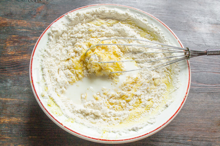 Finishing the Cake Batter with Milk Adding milk to the cake batter in a bowl and whisking until smooth.