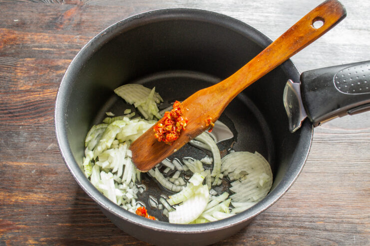 Sautéing finely chopped onions in a pot to start the soup base. Finely chopped onions being sautéed in a pot with hot oil.