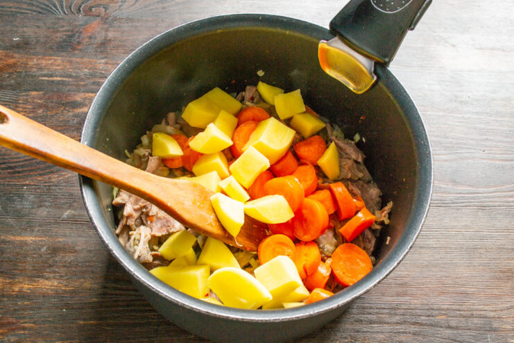 Adding diced potatoes to the soup. Diced potatoes being added to the soup pot with other vegetables.
