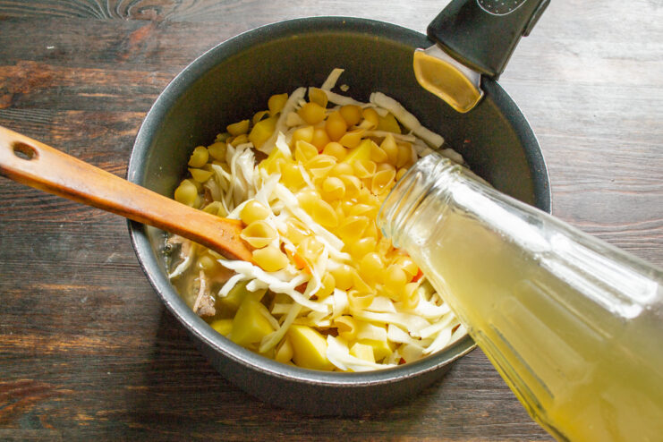 Pouring broth into the pot to complete the soup. Chicken or meat broth being poured into the pot with all the soup ingredients.