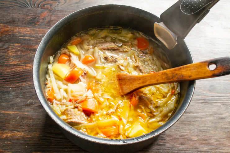 Simmering the soup with the lid on for 20 minutes. A pot of soup simmering on the stove with a lid on it.