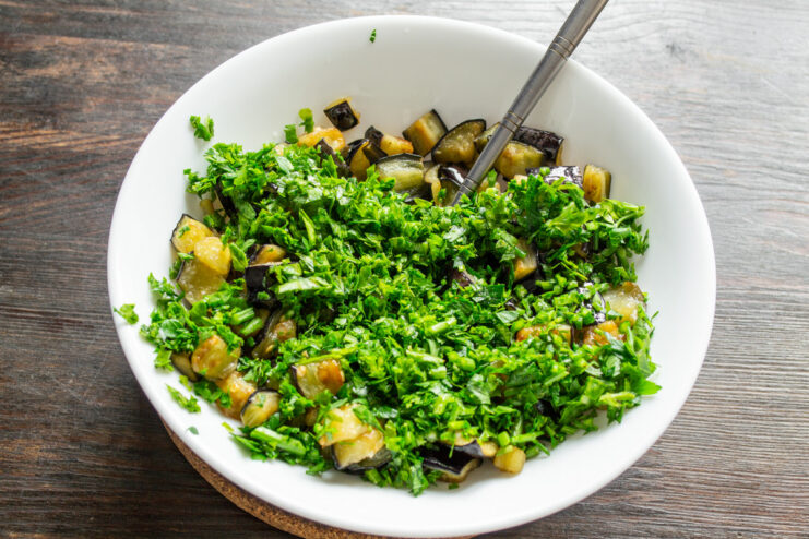 Adding Freshly Chopped Parsley for Flavor and Color Adding a handful of freshly chopped parsley to a bowl of fried eggplant.