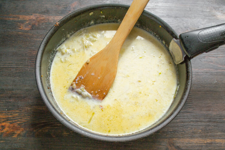 Finishing the Cream Sauce with Cream and Nutmeg Whisking cream into the sauce in a skillet to create a smooth consistency.