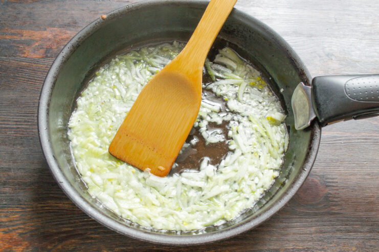 Sautéing Onions for the Savory Filling Finely diced onions being sautéed in a skillet with oil.