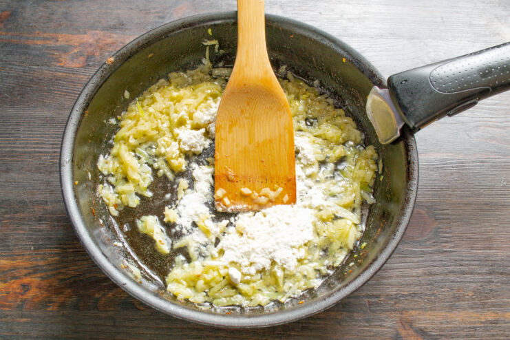 Sautéing Onions Until Soft for the Cream Sauce Diced onions being sautéed in butter in a skillet until translucent.