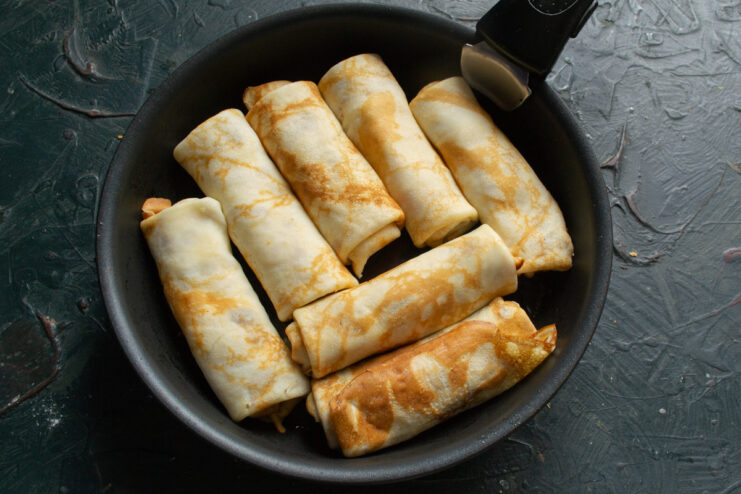 Frying the Stuffed Blinchiki Until Crispy and Golden Placing folded, stuffed blinchiki seam-side down into a hot, buttered skillet.