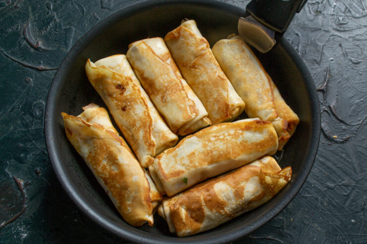 Serving Hot, Golden Blinchiki with a Dollop of Smetana Golden-brown fried blinchiki on a plate, served with a dollop of smetana (sour cream).