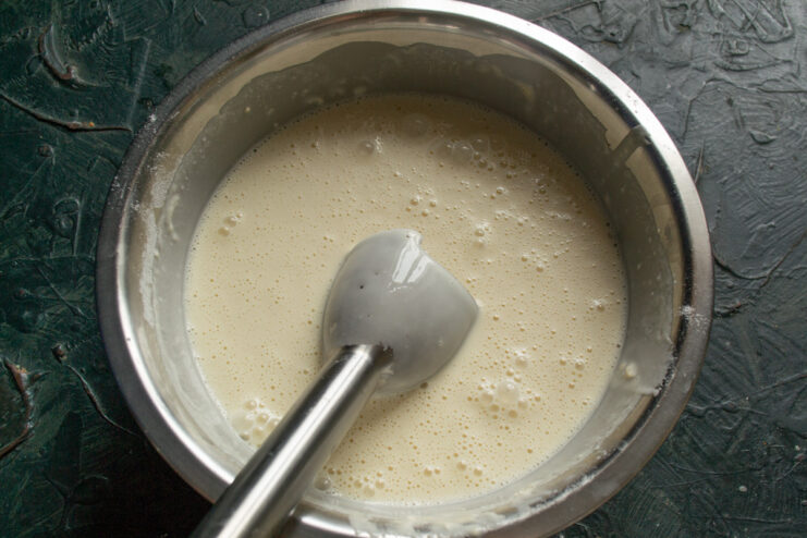 Whisking the Batter Until Smooth for Perfect Blinchiki Whisking the blinchiki batter in a glass bowl until it's smooth and creamy.