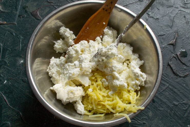 Mixing Grated Potato with Soft Tvorog for the Filling Combining grated potatoes with soft tvorog (farmer's cheese) in a bowl.