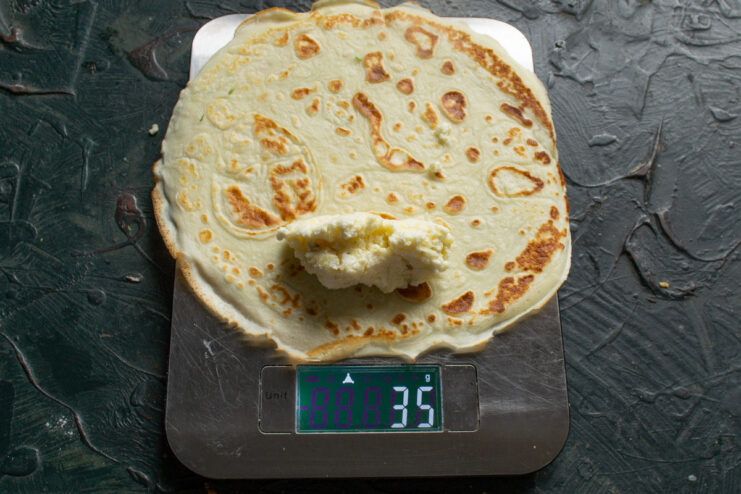 Placing the Savory Filling onto a Freshly Made Blin A spoonful of the potato and tvorog filling placed on the edge of a thin crepe.