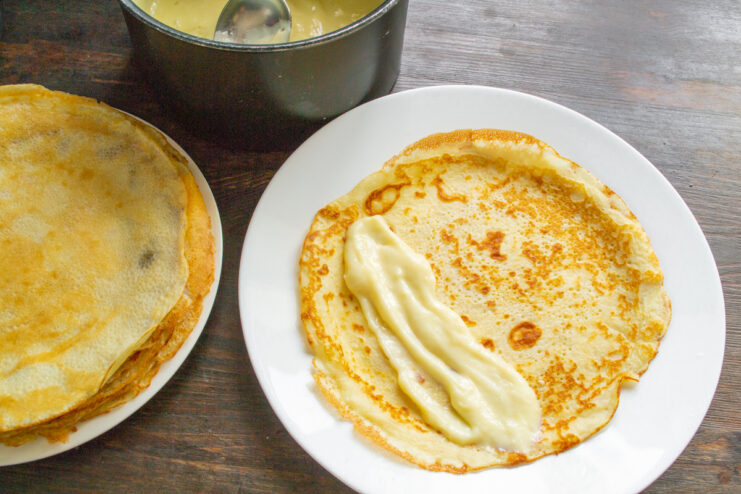 Spreading lemon custard onto a thin pancake before rolling it up.