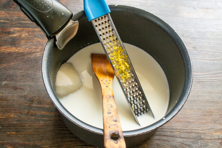 Ingredients for lemon custard, including milk, sugar, and lemon zest, in a saucepan.