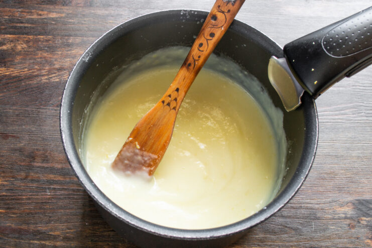 Pouring the egg and flour mixture into a saucepan of hot milk while whisking.