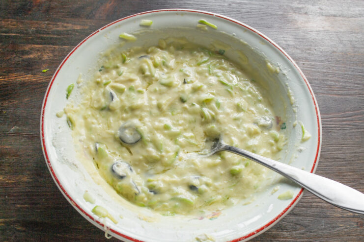 Mixing the Zucchini Pancake Batter A bowl with the fully mixed zucchini pancake batter with cheese and olives.