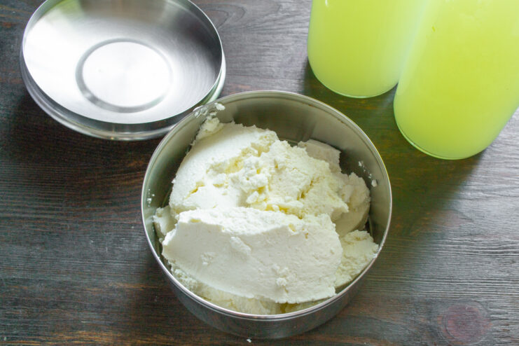 Freshly Separated Whey for Bliny Batter A clear bowl filled with yellowish whey, a byproduct of making tvorog, ready to be used or stored.