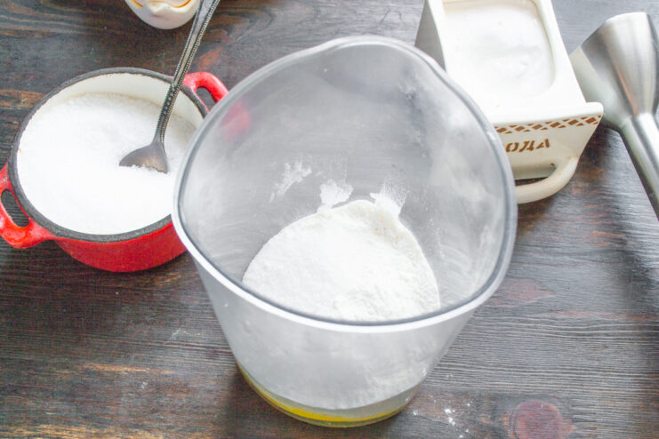 Seasoning the Bliny Batter with Salt, Sugar, and Soda Adding salt, sugar, and baking soda to the flour and egg mixture in the blender cup.