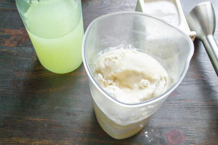 Adding Whey to Create a Tender Bliny Batter Pouring whey into the blender cup with other ingredients for the bliny batter.