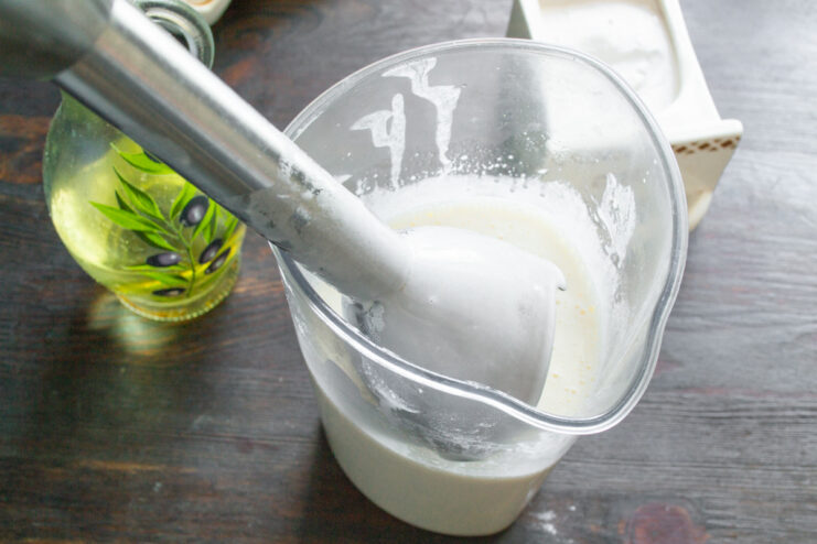 Blending the Bliny Batter Until Smooth Using an immersion blender to mix the bliny batter ingredients in a cup until smooth and creamy.