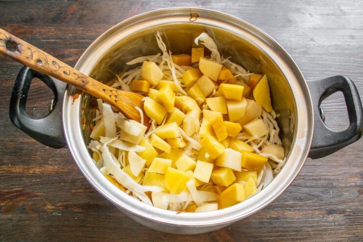 Adding potatoes and cabbage to the soup pot Diced potatoes being added to the pot with shredded cabbage.