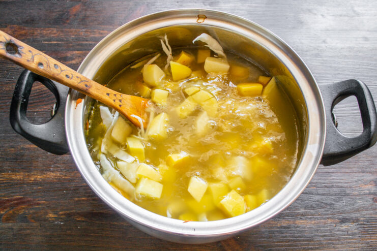 Using a rich broth as the foundation for your borscht Pouring broth into a pot with vegetables for borscht.