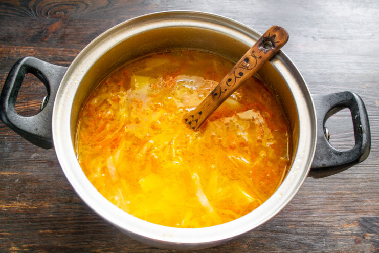 Simmering the borscht until all vegetables are perfectly tender Borscht simmering gently in a large pot on the stove.