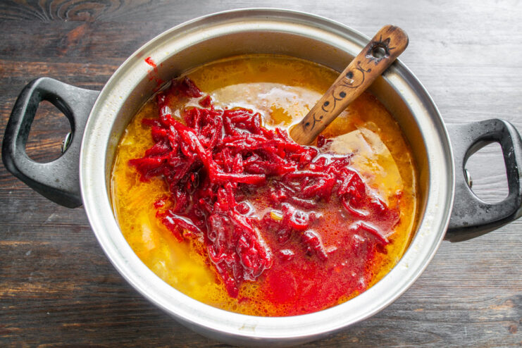 The final step: adding the beet mixture to give borscht its iconic color Adding the cooked beet and tomato mixture to the soup pot.