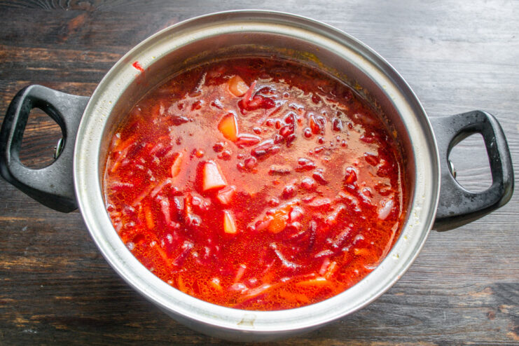 Pro tip: Season and heat the borscht at the end to preserve its color Seasoning the finished borscht in the pot with a spoon.