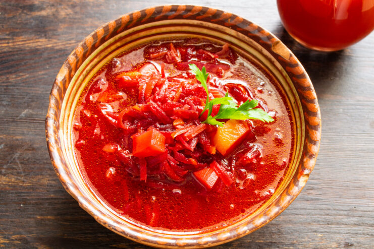 Garnishing and serving a perfect bowl of hot borscht A bowl of hot borscht being garnished with fresh green onions before serving.