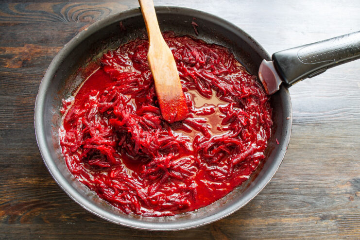 Simmering beets and tomato juice to develop deep flavors for the soup Beets simmering in tomato juice in a pan.