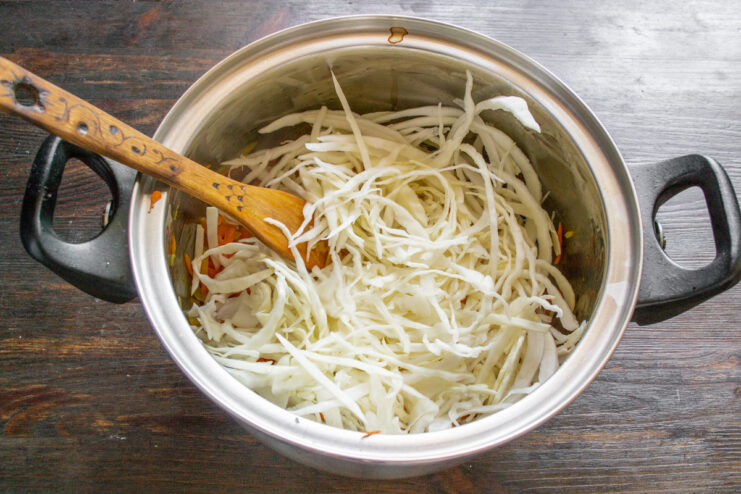 How to thinly shred cabbage for borscht A pile of thinly shredded white cabbage on a cutting board.