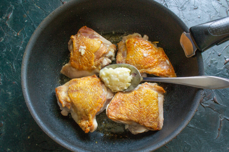 Golden-brown seared chicken pieces being flipped in a skillet.