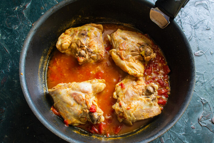 A skillet with Chakhokhbili covered with a lid, simmering on the stove.