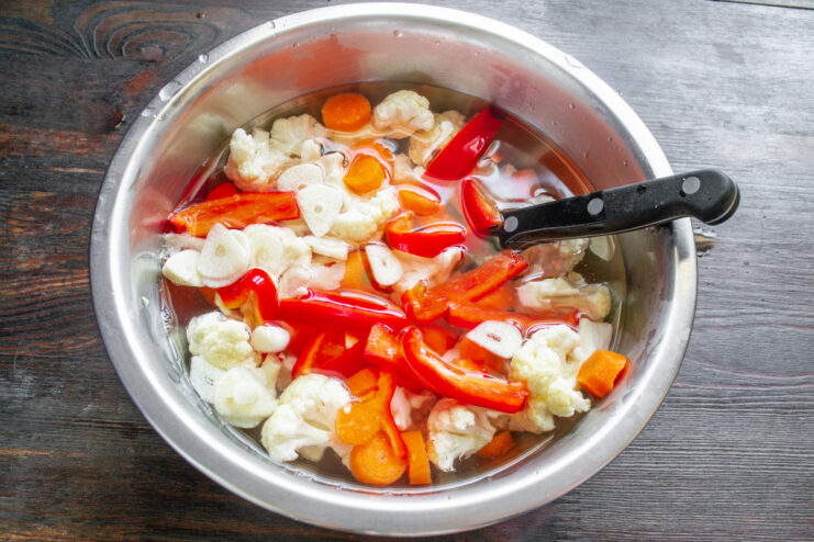 Step 5: Blanching the vegetables to prepare them for the marinade A pot filled with hot water and the vegetable mix of cauliflower, carrots, and peppers.