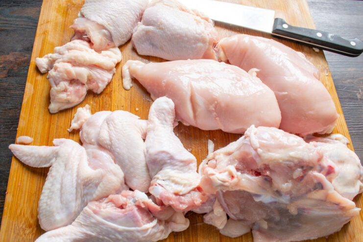 Preparing chicken parts for a flavorful broth Raw chicken parts including carcass, neck, wings, and drumsticks on a cutting board.