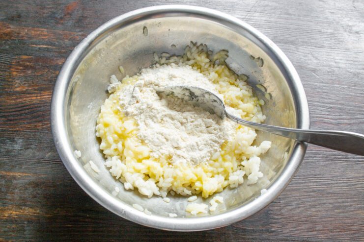 Adding rice flour to create the dumpling dough Adding a spoonful of rice flour to the rice and egg mixture in a bowl.
