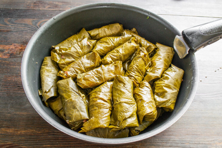 Arranging Dolma rolls snugly in a pot before cooking Neatly arranged uncooked Dolma rolls filling the bottom of a wide pot.