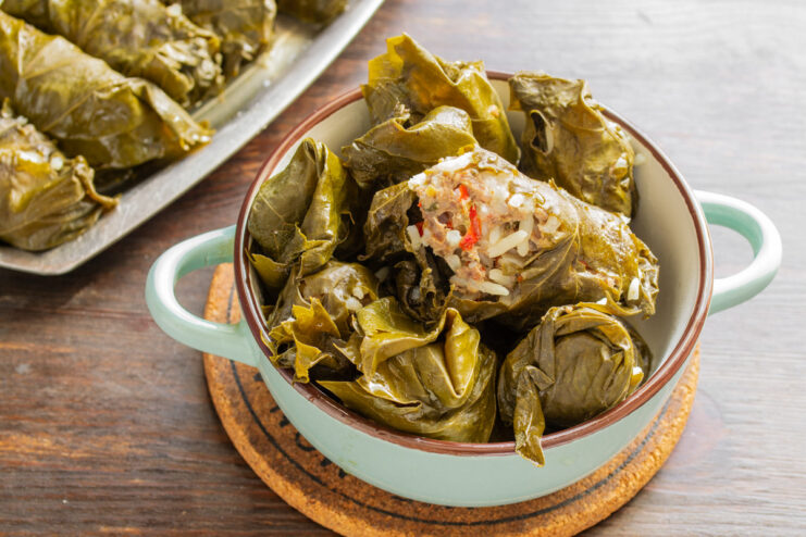 How to serve Dolma: with yogurt or a creamy herb sauce A serving of cooked Dolma on a plate, garnished with fresh herbs and a side of creamy yogurt sauce.