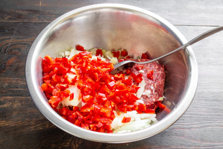 How to prepare bell peppers for the Dolma filling A red bell pepper being finely diced on a cutting board for the dolma filling.