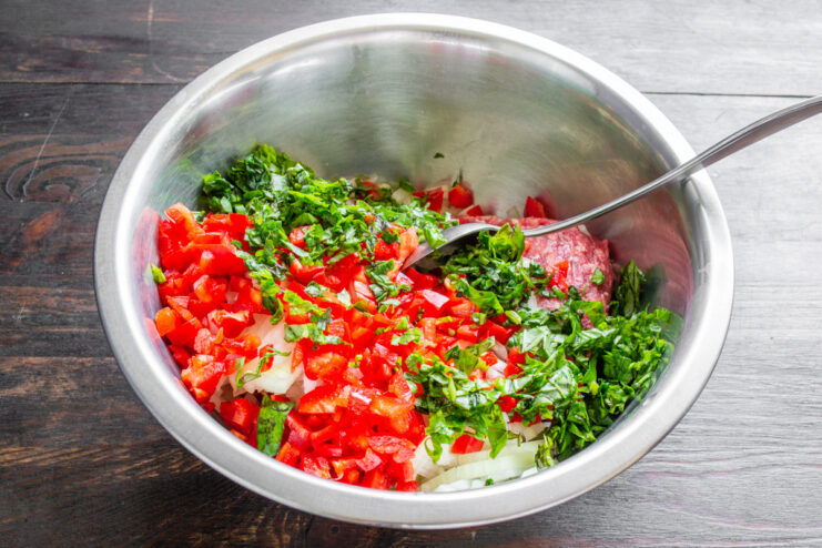 Adding fresh herbs to the Dolma filling A bunch of fresh cilantro being finely chopped on a cutting board.