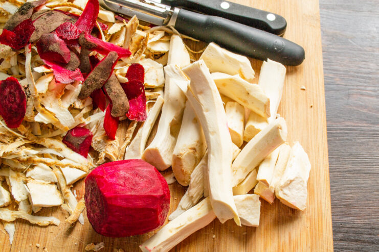 Step 1: Preparing the Vegetables for the Horseradish Sauce Hands peeling a horseradish root with a vegetable peeler next to a peeled beet.