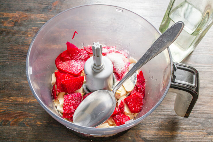 Seasoning the Horseradish Sauce with Vinegar, Salt, and Sugar Adding vinegar, salt, and sugar to the blender bowl with horseradish and beets.