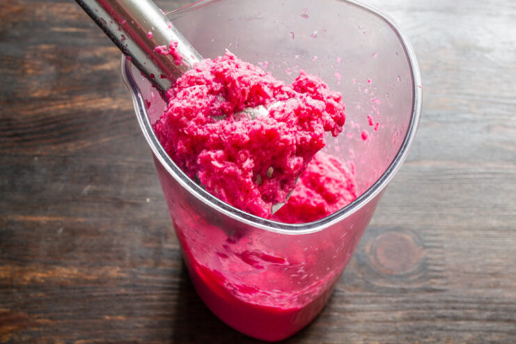 Using an Immersion Blender for a Smoother Sauce Texture Using an immersion blender to process the horseradish and beet mixture in a tall container.
