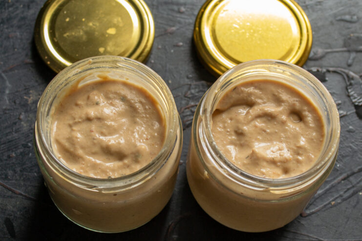 Properly Filling Sterilized Jars with Chicken Pâté for Canning Filling a sterilized glass jar with the chicken pâté mixture using a spoon.