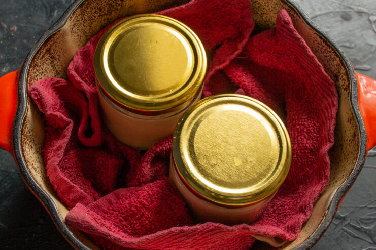 Preparing the Jars for Water Bath Canning to Preserve the Pâté Sealed jars of chicken pâté placed in a large pot and being covered with water.