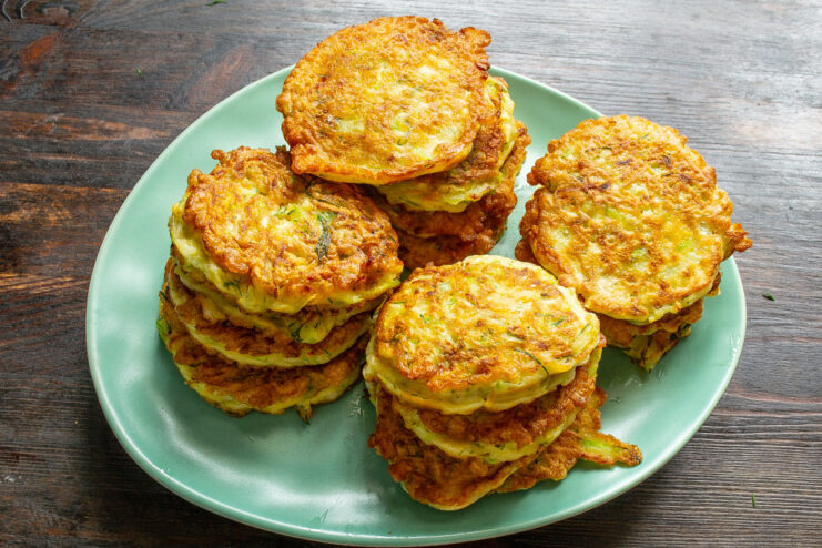 Serving Hot and Fresh Zucchini Carrot Draniki A stack of freshly fried zucchini and carrot draniki on a plate, ready to be served.